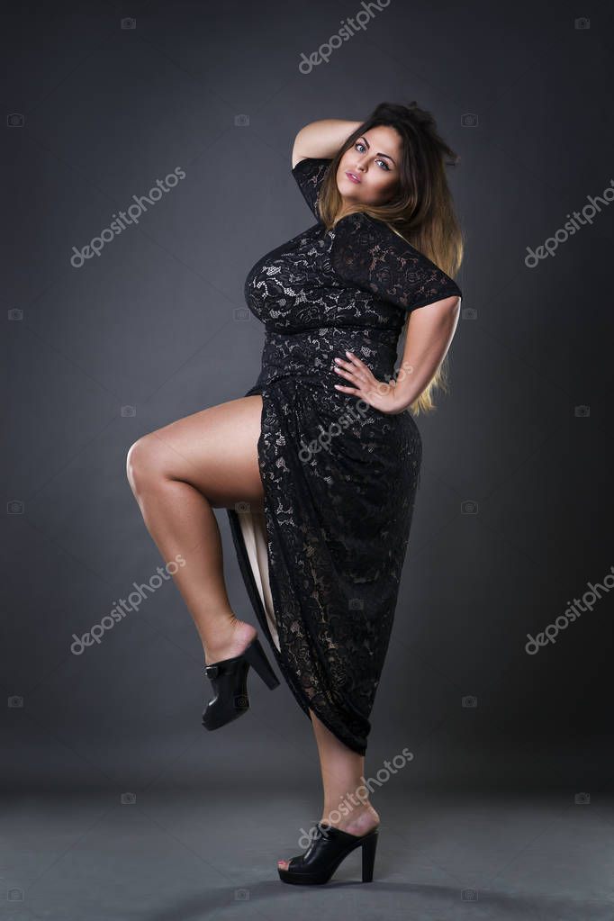 Young beautiful plus size model in black dres, xxl woman on gray