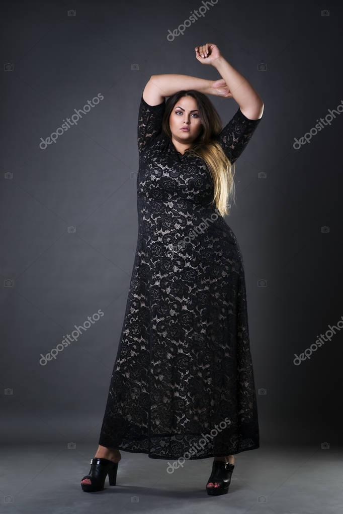 Young beautiful plus size model in black dres, xxl woman on gray