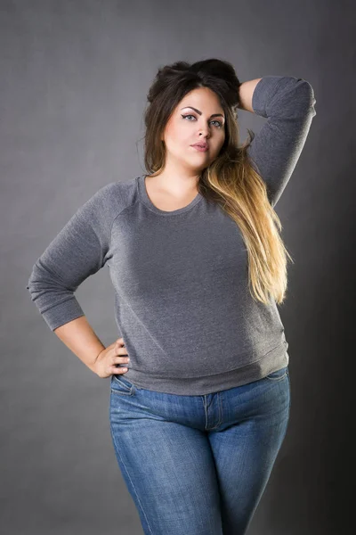 Jovem modelo bonito plus size em jeans azul, mulher xxl em fundo cinza — Fotografia de Stock