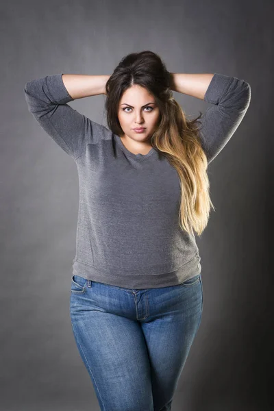 Joven hermosa modelo de talla grande en vaqueros azules, xxl mujer sobre fondo gris — Foto de Stock