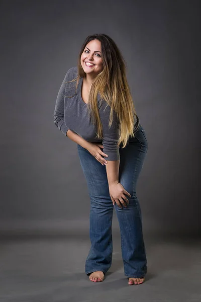 Junge schöne Plus-Size-Modell in blauen Jeans, XL-Frau auf grauem Studiohintergrund — Stockfoto