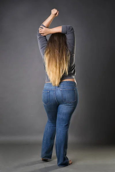Плюс модель розміру в блакитних джинсах, Xl жінка на сірому студійному фоні — стокове фото