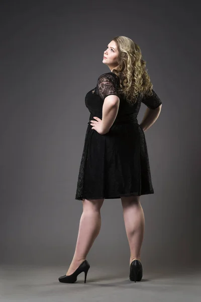 Giovane bella plus size modello in draghe nere, donna xxl su sfondo grigio studio — Foto Stock