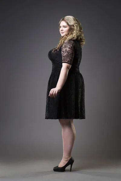 Giovane bella plus size modello in draghe nere, donna xxl su sfondo grigio studio — Foto Stock