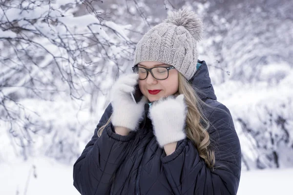 Güzel genç kadın kış park, artı boyutu model karlı bir arka plan üzerinde bir cep telefonunda söz — Stok fotoğraf