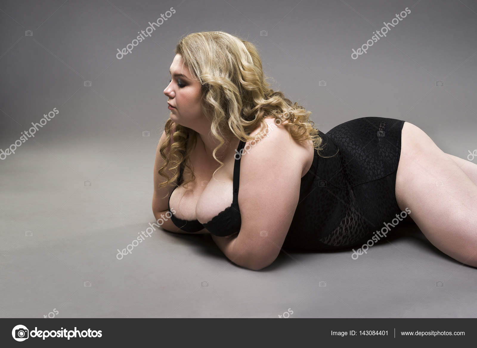 Young beautiful blonde plus size model with big natural breasts in xxl woman on gray studio background Photo ©starast 143084401