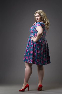 Genç güzel mutlu sarışın artı boyutu model xxl kadın gri studio arka plan üzerinde elbise ve ayakkabı,