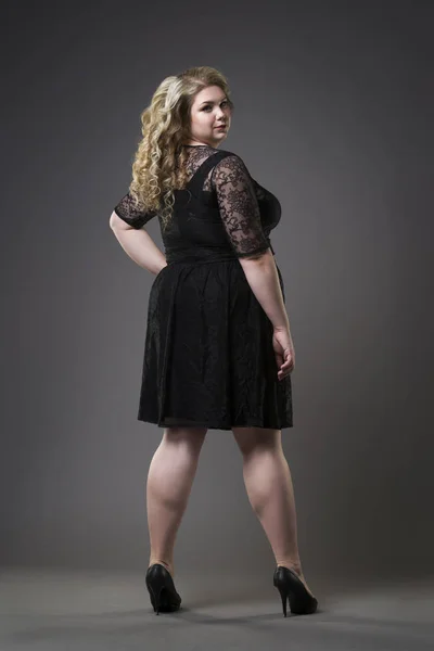 Giovane bella plus size modello in draghe nere, donna xxl su sfondo grigio studio — Foto Stock