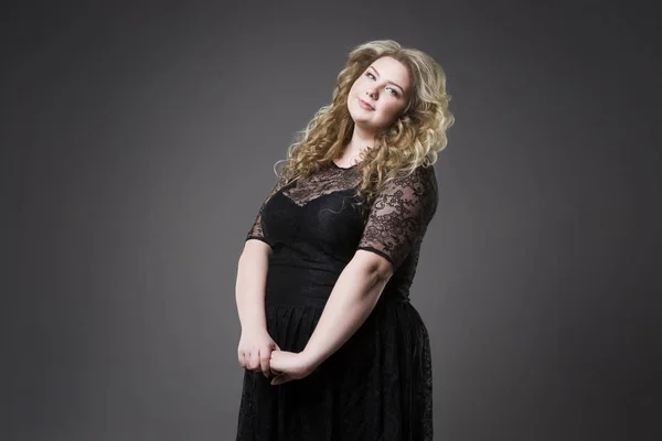 Junge schöne Blondine plus Size-Modell in schwarz dres, XL-Frauenporträt auf grauem Studiohintergrund — Stockfoto