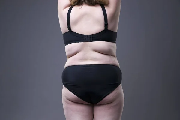 Modèle taille plus en lingerie noire, corps féminin en surpoids, femme grasse avec cellulite sur les fesses sur fond gris — Photo