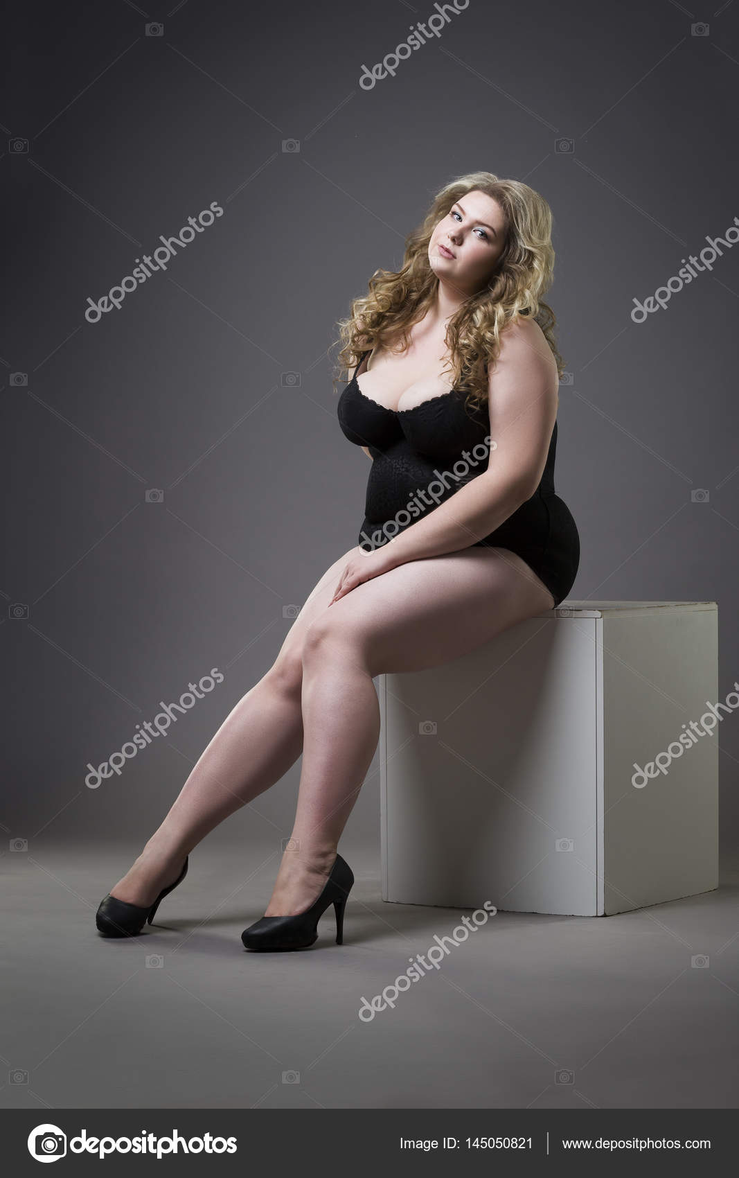 Young beautiful blonde plus size model in shapewear, woman in slimming underwear on gray studio Stock Photo by ©starast