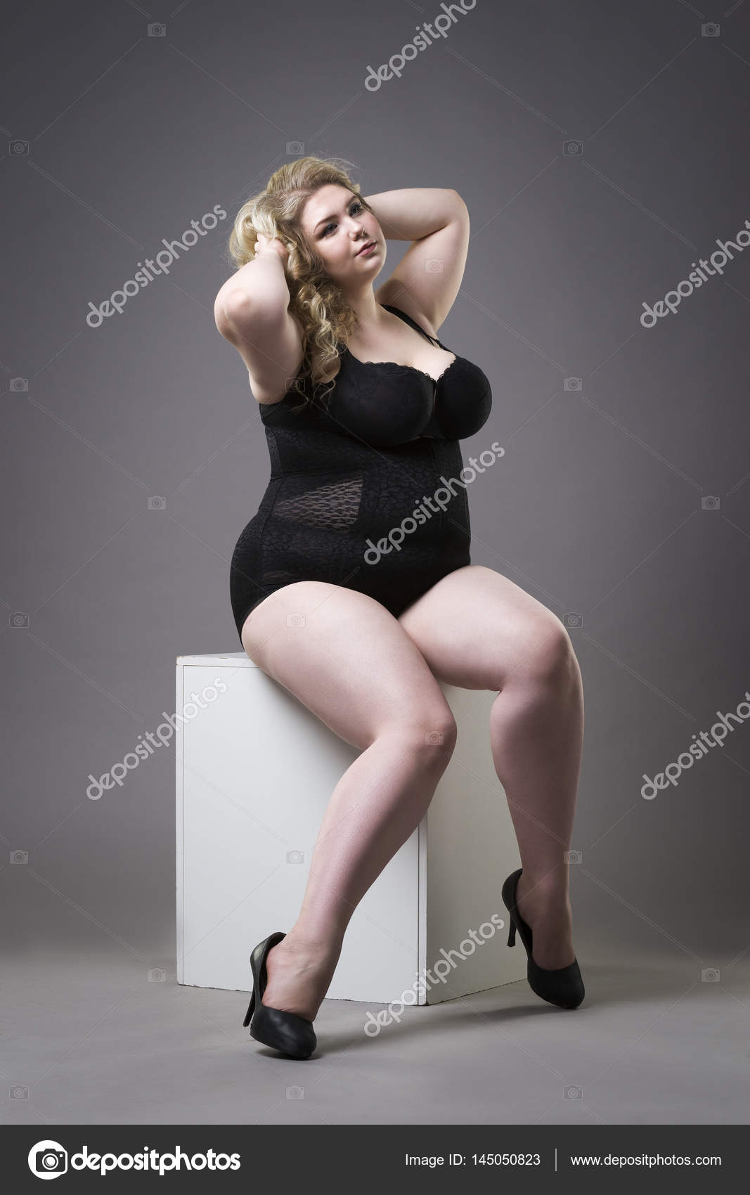 Young beautiful blonde plus size shapewear, xxl woman in underwear gray studio background Stock Photo by ©starast 145050823