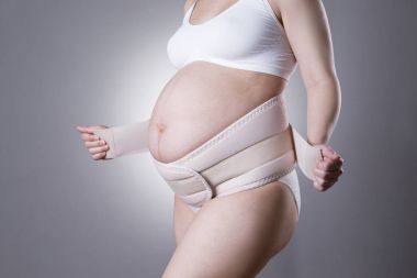 Pregnant woman in white underwear with orthopedic support belt, pregnancy bandage clipart
