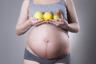 Gebelik ve beslenme - meyveler el üstünde olan hamile kadın gri arka plan, vejetaryen diyet