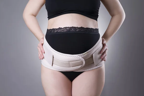 Schwangere in schwarzer Unterwäsche mit orthopädischem Stützgürtel, Schwangerschaftsverband — Stockfoto