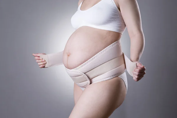 Mujer embarazada en ropa interior blanca con cinturón de soporte ortopédico, vendaje de embarazo — Foto de Stock