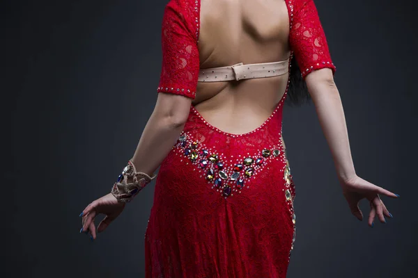Jeune belle exotique orientale femmes effectue la danse du ventre en robe rouge ethnique avec dos ouvert sur fond gris — Photo