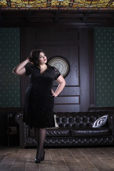 Модель plus size в черном вечернем платье, толстая женщина в роскошном интерьере, избыточный вес женского тела, портрет в полный рост — стоковое фото