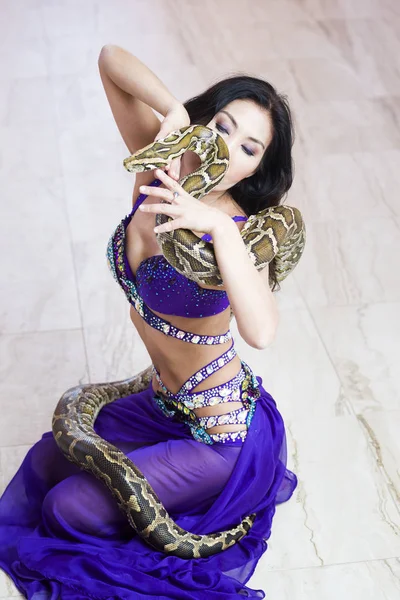 Взрослая женщина в сценическом костюме выступает с большой змеей — стоковое фото