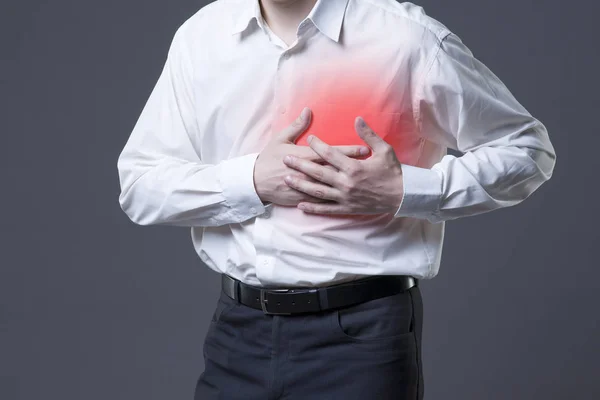 Сердечный приступ, мужчина с болью в груди на сером фоне — стоковое фото