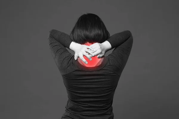 Боль в шее, женщина с болью в спине на сером фоне — стоковое фото