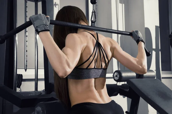 Entrenamiento de mujer fitness sexy joven con máquina de entrenamiento en el gimnasio —  Fotos de Stock