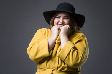 Sarı ceket ve siyah şapka boyutu moda modeli, gri arka plan, kilolu kadın bedeni üzerinde kadın şişko