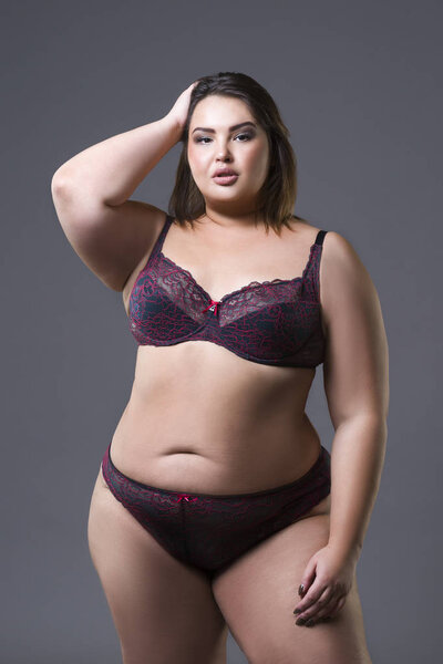 Plus size fashion model in underwear, young fat woman on gray background, overweight female body