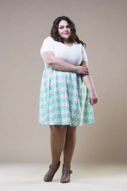 Artı günlük kıyafetlerle manken boy, bej renkli stüdyo arka planda şişman kadın, şişman kadın vücudu.