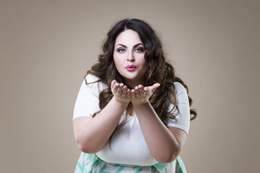 Artı boyutu moda model hava öpücük, bej renkli arka plan, kilolu kadın bedeni üzerinde şişman kadın gönderir