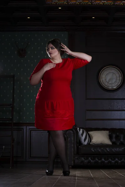 Plus size fashion model in red evening dress, fat woman on luxury interior — Stock Photo, Image