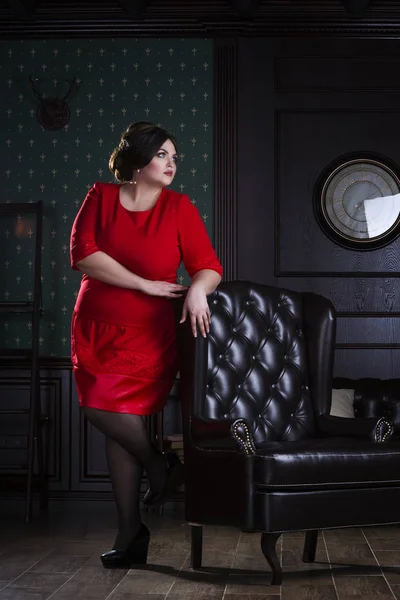 Модель plus size в красном вечернем платье, толстая женщина на роскошном интерьере — стоковое фото