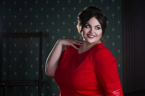 Plus size fashion model in red evening dress, fat woman on luxury interior