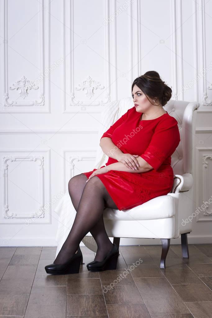 Plus size fashion model in red evening dress, fat woman on luxury interior