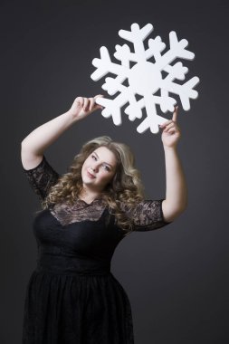 Plus size woman in black dres with snowflake on gray background clipart