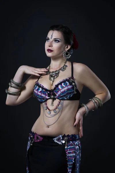 Women performs belly dance in ethnic dress on black background