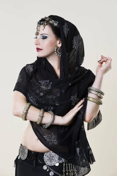 Kadınlar bej renkli arka plan üzerinde etnik elbiseli oryantal dans gerçekleştirir