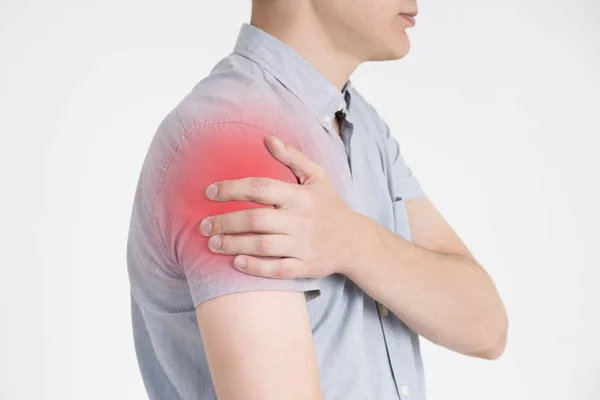 Uomo con dolore alla spalla su sfondo grigio — Foto Stock