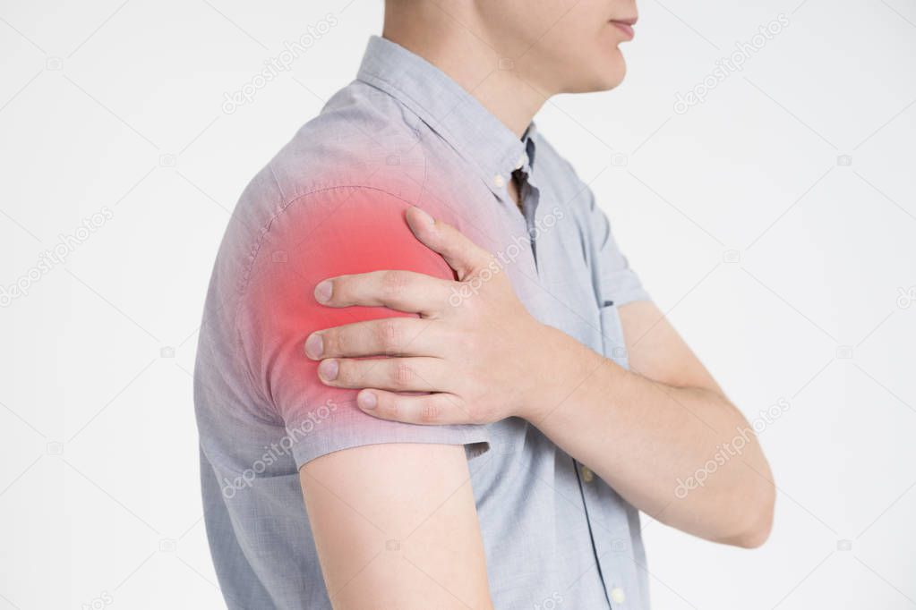 Man with pain in shoulder on gray background
