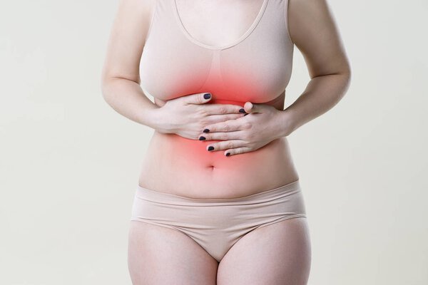 Woman with abdominal pain, stomachache on beige background
