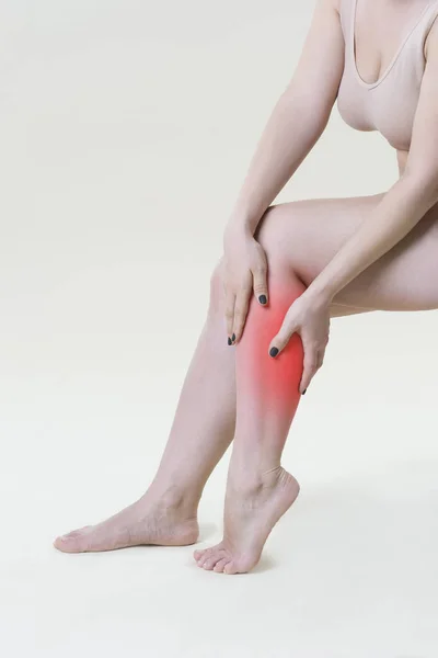 Schmerzen in den Beinen der Frau, Massage der weiblichen Füße auf beigem Hintergrund — Stockfoto