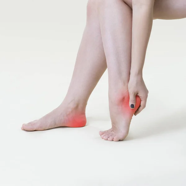 Smärta i kvinnans ben, massage av kvinnliga fötterna på beige bakgrund — Stockfoto