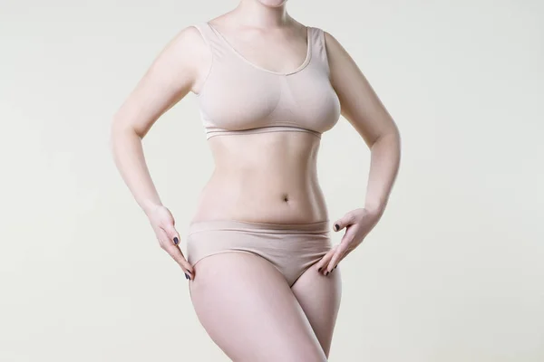 Donna in biancheria intima beige su sfondo studio, cellulite su corpo femminile — Foto Stock