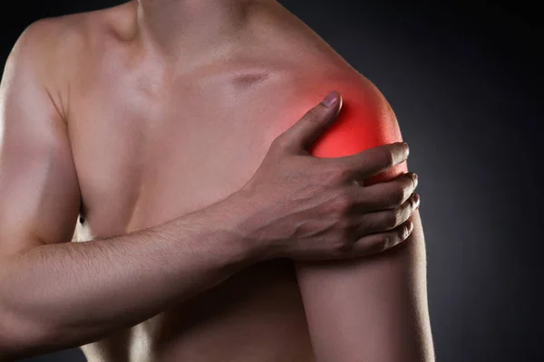 Uomo con dolore alla spalla su sfondo nero — Foto Stock
