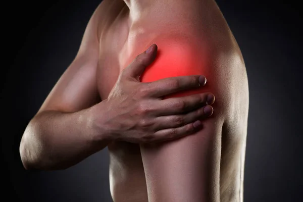 Homem com dor no ombro no fundo preto — Fotografia de Stock