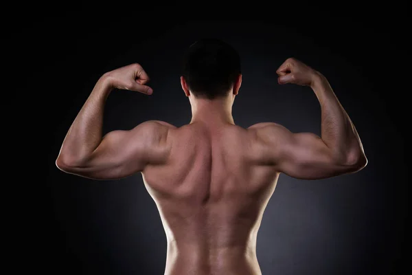 Knappe bodybuilder poseren op zwarte achtergrond, perfecte gespierde man terug — Stockfoto