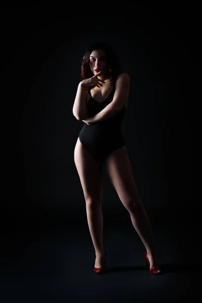 Vacker sexig kvinna i bodysuit poserar på svart bakgrund, lågmäld studio skott — Stockfoto
