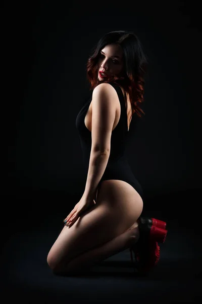 Vacker sexig kvinna i bodysuit poserar på svart bakgrund, lågmäld studio skott — Stockfoto