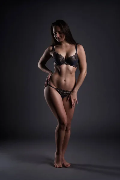 Schöne sexy Frau in Dessous posiert auf grauem Studiohintergrund, perfekter weiblicher Körper — Stockfoto