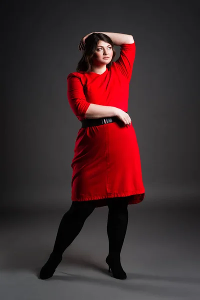 Plus velikost fashion model v červených šatech, tlustá žena na šedém pozadí, nadváhou ženské tělo — Stock fotografie